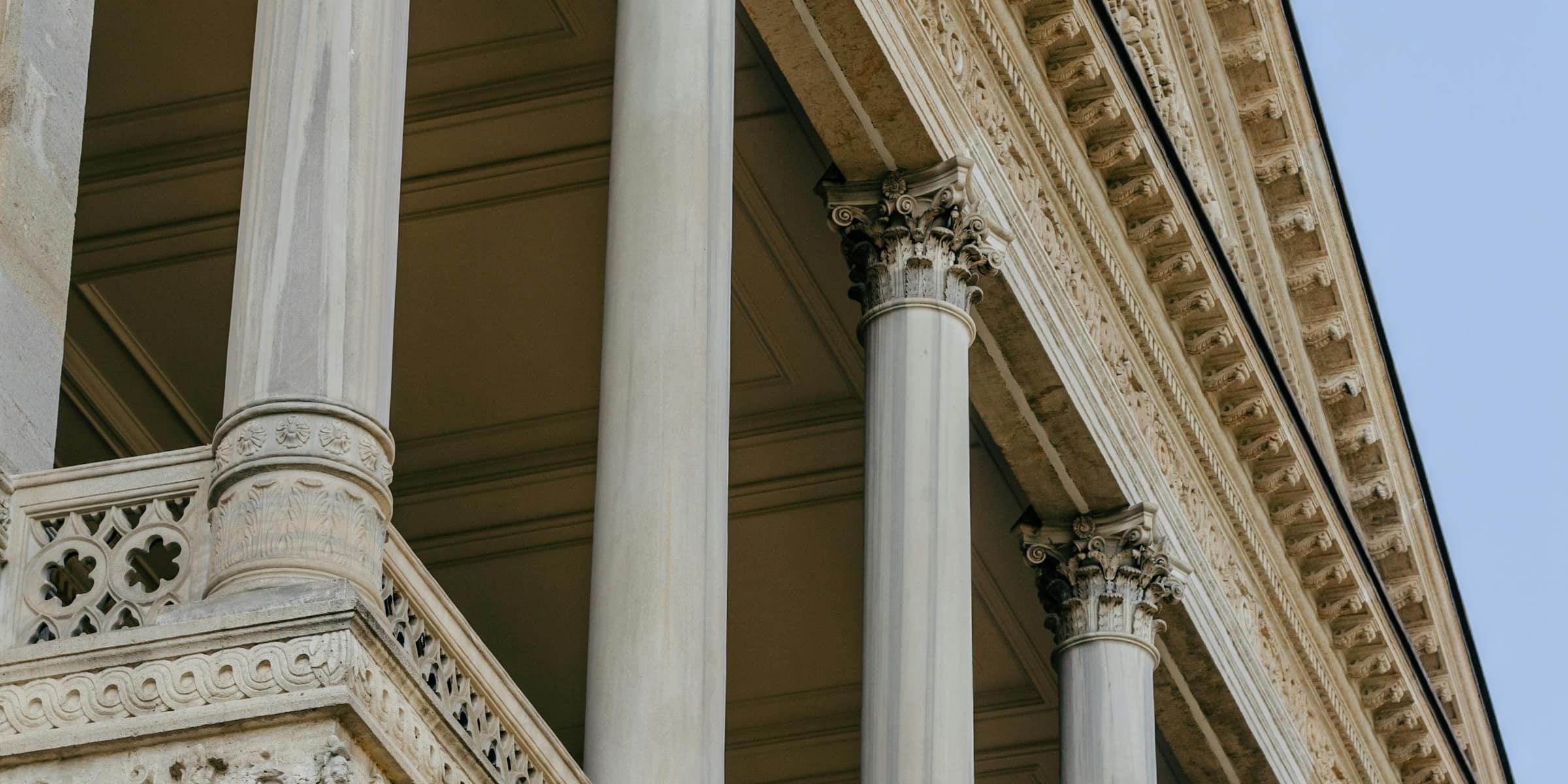 A grand classical limestone portico with columns against a clear sky