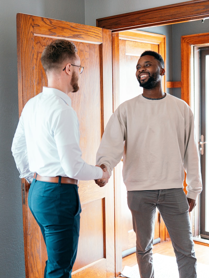 Two people shaking hands at a front door
